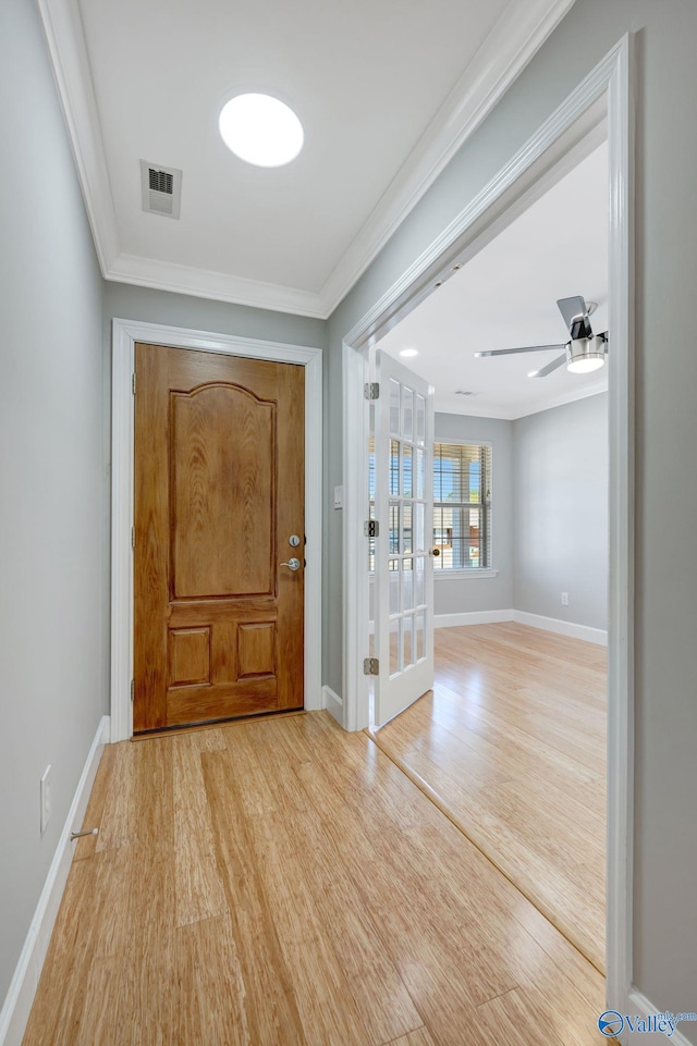 foyer featuring light wood finished floors, visible vents, crown molding, and baseboards