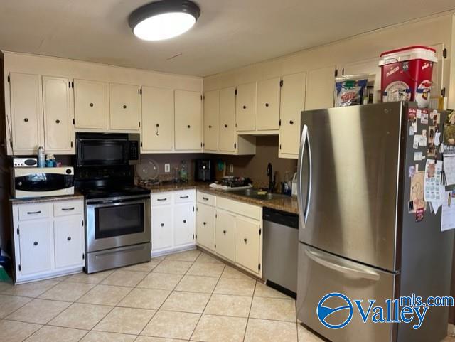 kitchen with dark countertops, appliances with stainless steel finishes, white cabinets, and a sink