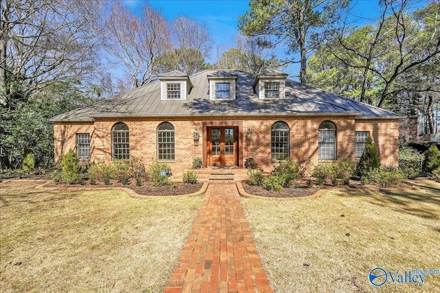 view of front facade with french doors, brick siding, a standing seam roof, metal roof, and a front lawn