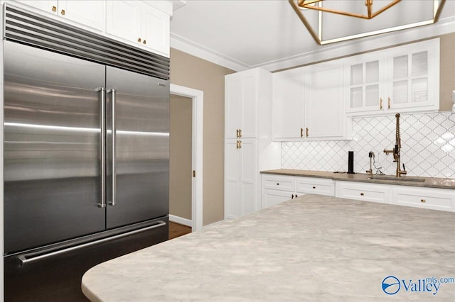 kitchen featuring glass insert cabinets, white cabinets, stainless steel built in fridge, and backsplash