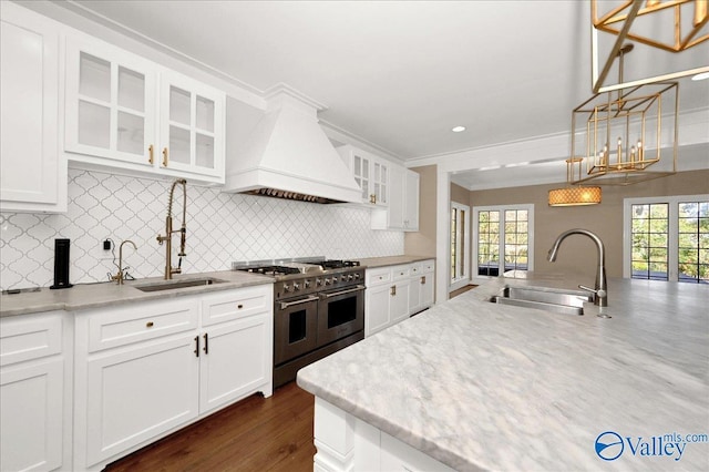 kitchen featuring premium range hood, range with two ovens, a sink, and glass insert cabinets