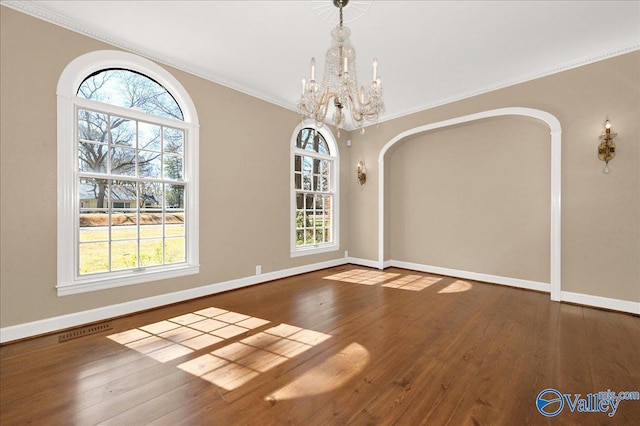 unfurnished dining area featuring baseboards, ornamental molding, a chandelier, and wood finished floors