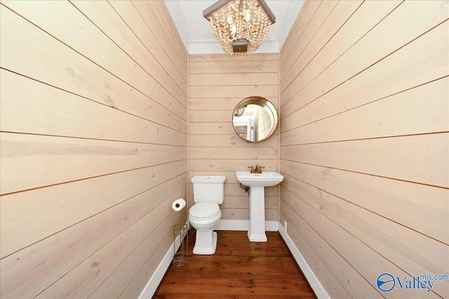 half bath featuring wood finished floors, toilet, and wooden walls