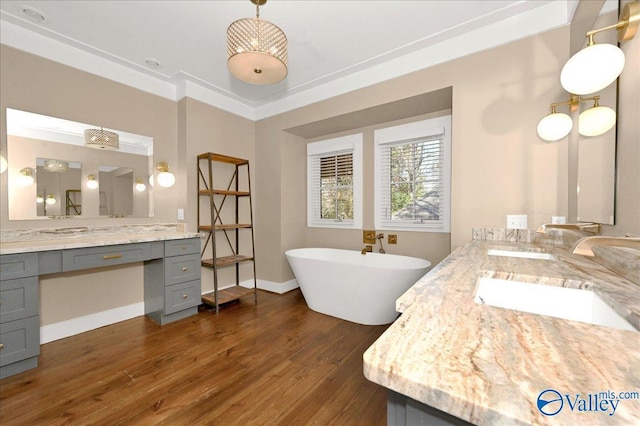 full bathroom featuring a freestanding tub, crown molding, vanity, and wood finished floors