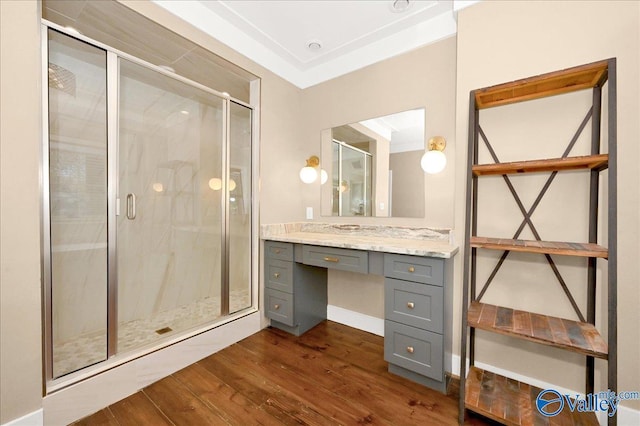 full bathroom featuring a stall shower, wood finished floors, and vanity