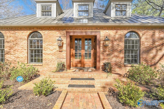 property entrance with a standing seam roof, brick siding, and french doors