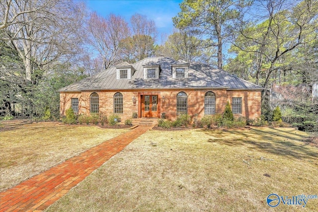 view of front of house featuring a front lawn, a standing seam roof, and brick siding