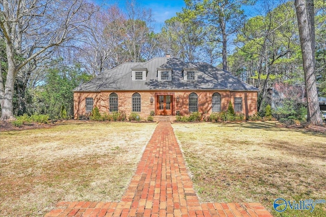 view of front of house featuring brick siding, metal roof, and a front yard