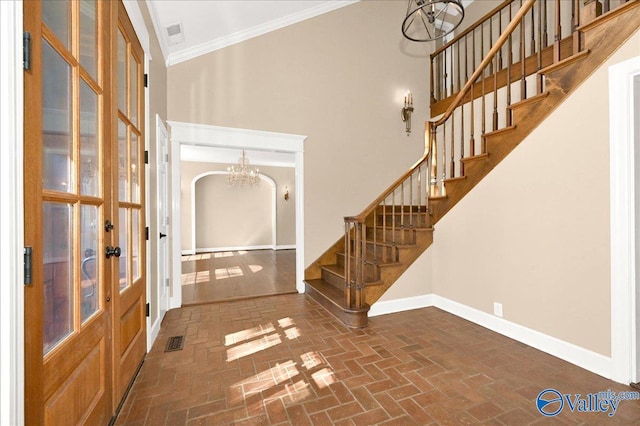 foyer entrance with a towering ceiling, visible vents, stairs, baseboards, and ornamental molding