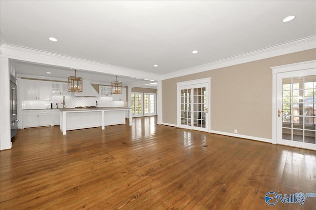 unfurnished living room with baseboards, dark wood finished floors, and crown molding