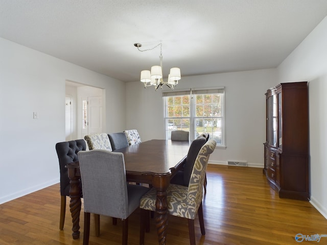 dining space with dark hardwood / wood-style floors and a chandelier