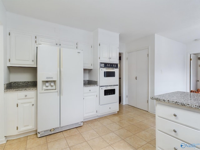 kitchen featuring white appliances, white cabinetry, and stone countertops