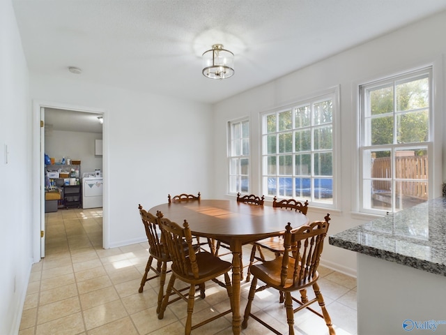 tiled dining space with washer / clothes dryer and a notable chandelier