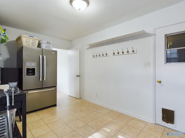 kitchen featuring stainless steel refrigerator with ice dispenser, a textured ceiling, and light tile patterned floors