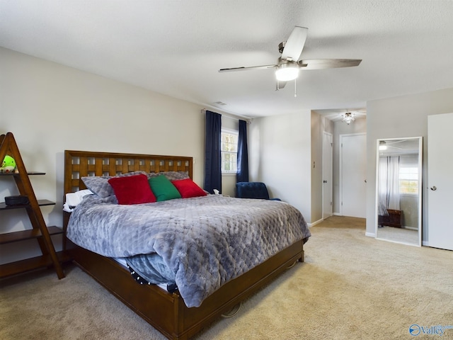 bedroom featuring multiple windows, light colored carpet, and ceiling fan