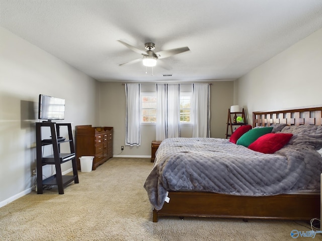 carpeted bedroom with ceiling fan and a textured ceiling