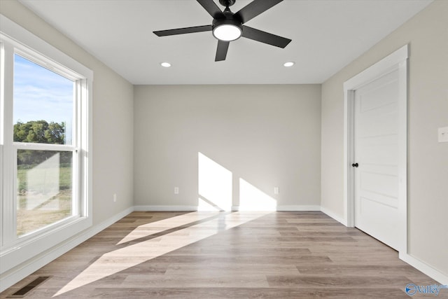 spare room featuring a healthy amount of sunlight, ceiling fan, and light hardwood / wood-style floors