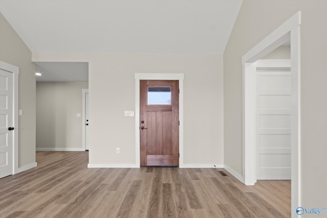 foyer entrance with lofted ceiling and light hardwood / wood-style floors