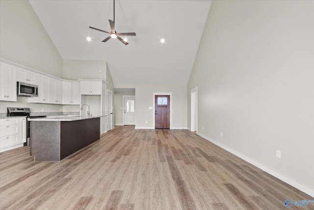 kitchen with appliances with stainless steel finishes, high vaulted ceiling, white cabinets, and light hardwood / wood-style flooring