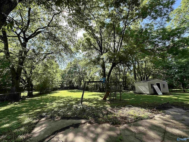 view of yard featuring a playground, an outdoor structure, and fence