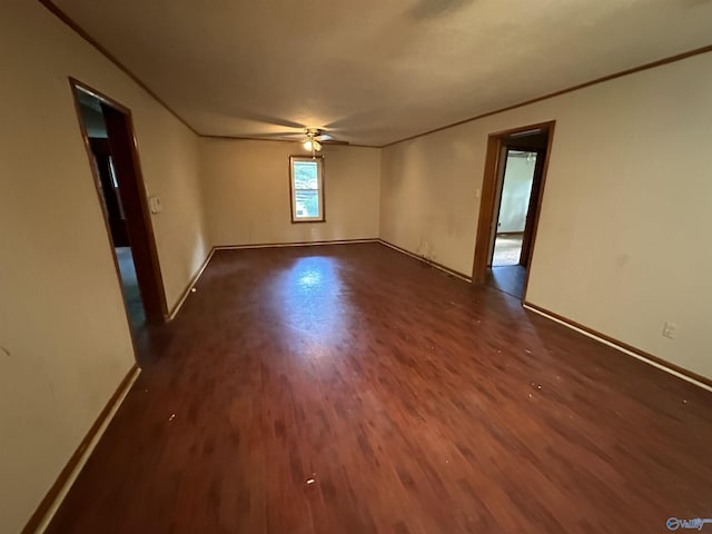 empty room featuring a ceiling fan, dark wood-style flooring, crown molding, and baseboards