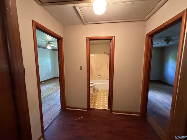 hall with wood finished floors, attic access, and baseboards