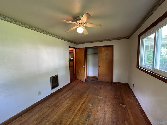 unfurnished bedroom with a fireplace, heating unit, a closet, baseboards, and hardwood / wood-style flooring