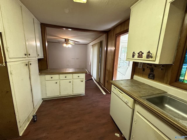 kitchen with white dishwasher, tile counters, dark wood finished floors, and a sink