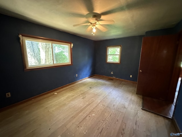 unfurnished bedroom with wood-type flooring, a ceiling fan, and baseboards