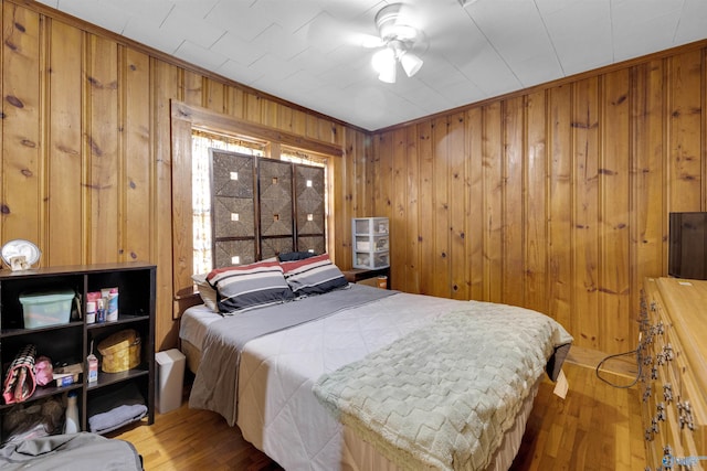 bedroom with ceiling fan, dark wood-type flooring, ornamental molding, and wooden walls