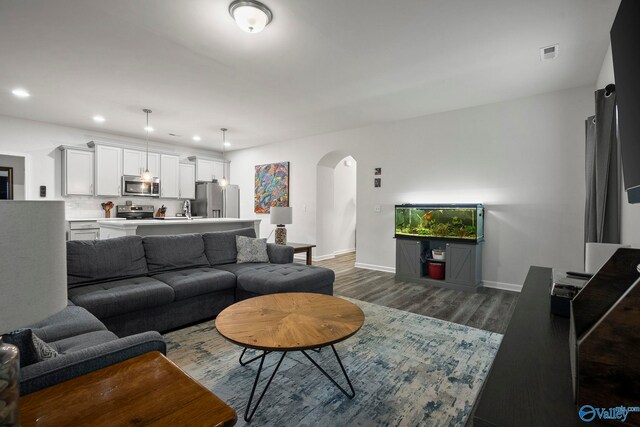 living area featuring recessed lighting, wood finished floors, visible vents, arched walkways, and baseboards