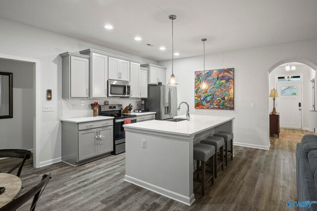 kitchen with dark wood finished floors, light countertops, gray cabinets, a sink, and appliances with stainless steel finishes