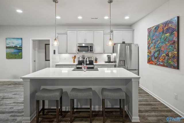 kitchen featuring a kitchen bar, tasteful backsplash, appliances with stainless steel finishes, and a kitchen island with sink