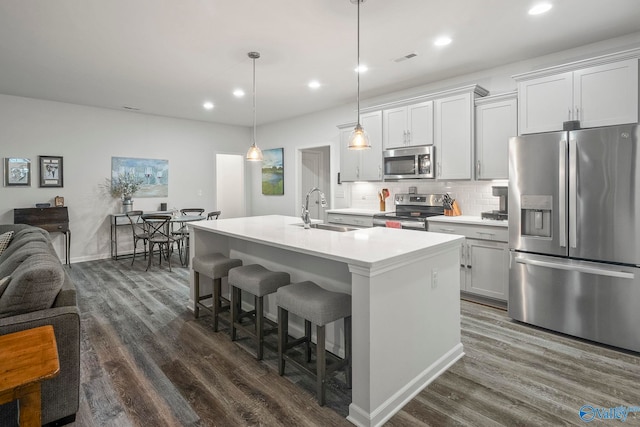 kitchen with stainless steel appliances, a kitchen breakfast bar, a sink, dark wood-style flooring, and open floor plan