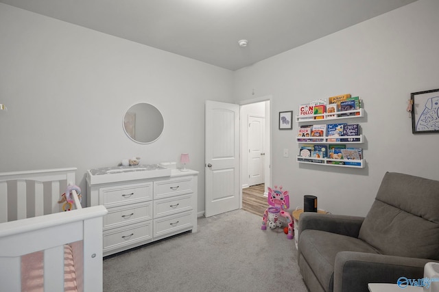 bedroom with a nursery area, baseboards, and light carpet
