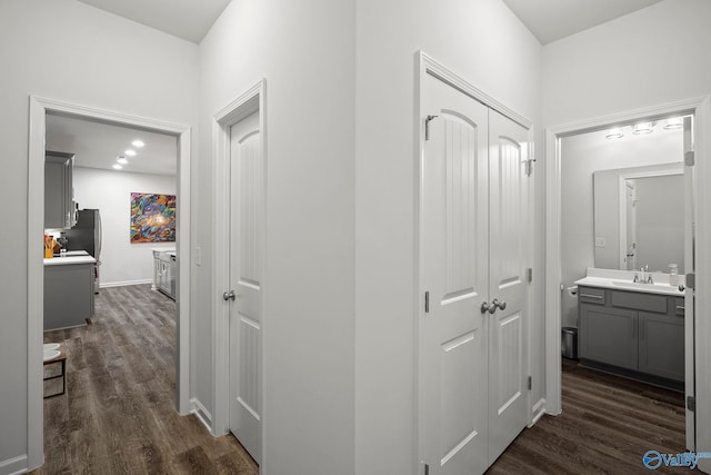 hallway with baseboards, a sink, and dark wood-style floors