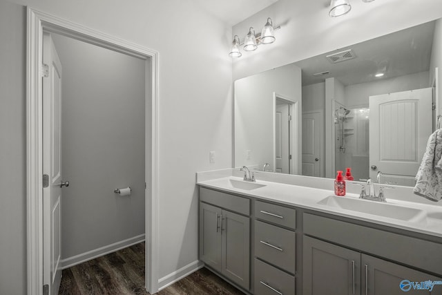 bathroom with wood finished floors, visible vents, a walk in shower, and a sink