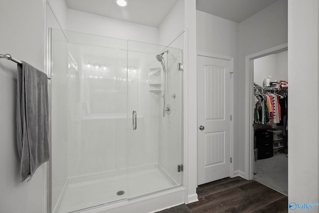 full bathroom featuring a walk in closet, wood finished floors, and a stall shower