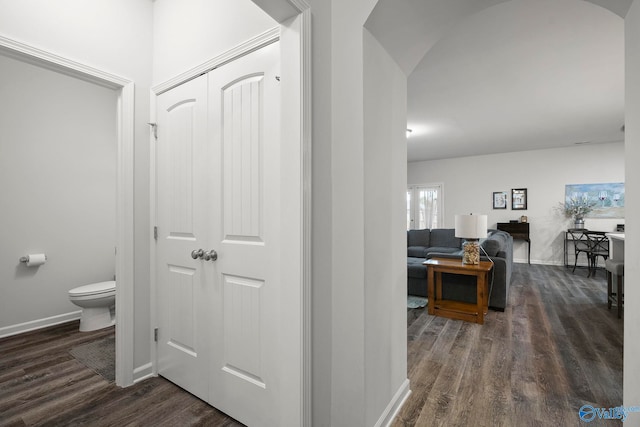hall with arched walkways, dark wood-style floors, and baseboards