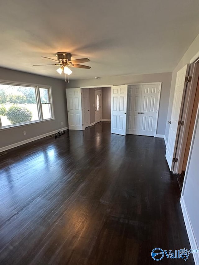 unfurnished bedroom with ceiling fan, multiple closets, and dark hardwood / wood-style floors