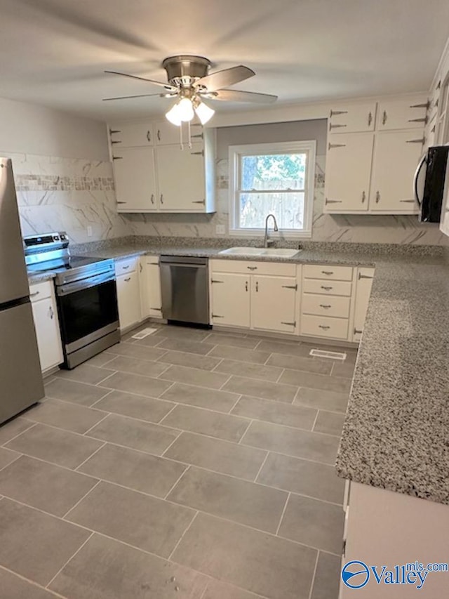 kitchen featuring sink, white cabinets, stainless steel appliances, backsplash, and light stone countertops