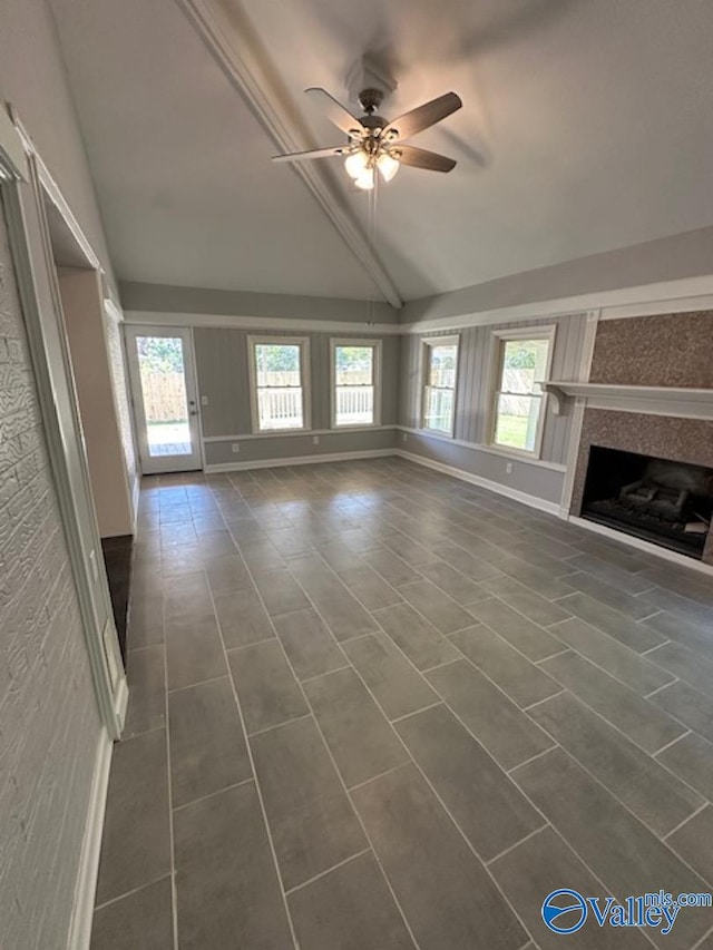 unfurnished living room featuring ceiling fan, dark tile patterned flooring, plenty of natural light, and vaulted ceiling