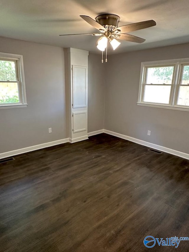 empty room featuring ceiling fan, dark hardwood / wood-style flooring, and a wealth of natural light