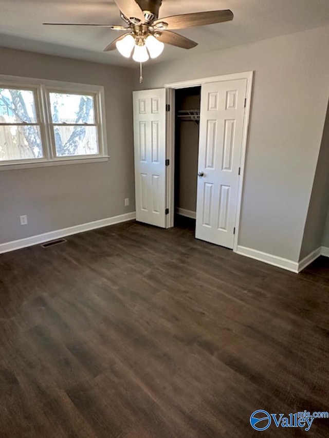 unfurnished bedroom with dark wood-type flooring, ceiling fan, and a closet