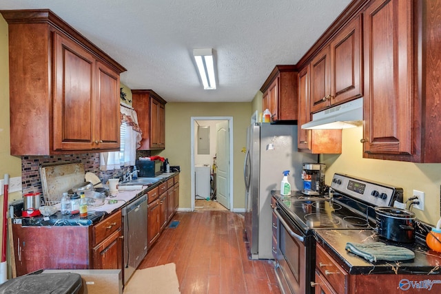 kitchen featuring stainless steel appliances, washer / dryer, light hardwood / wood-style floors, and a textured ceiling