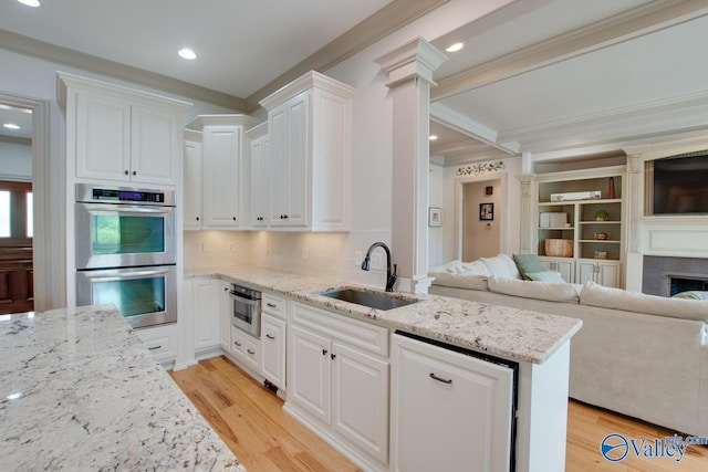 2602 Legacy Preserve Dr, Brownsboro, AL 35741 - kitchen with stainless steel double oven, a sink, open floor plan, crown molding, and white cabinetry