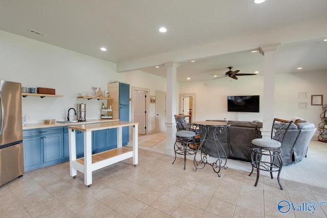 2602 Legacy Preserve Dr, Brownsboro, AL 35741 - kitchen with freestanding refrigerator, decorative columns, blue cabinetry, open shelves, and a ceiling fan