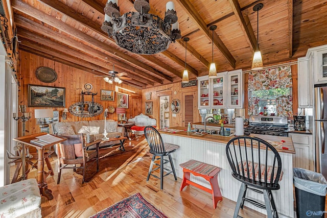 kitchen featuring wood ceiling, stainless steel range oven, hanging light fixtures, and white cabinets