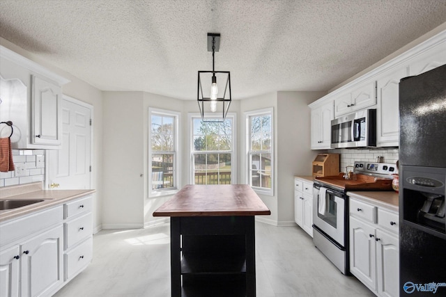kitchen with pendant lighting, white cabinetry, stainless steel appliances, and backsplash