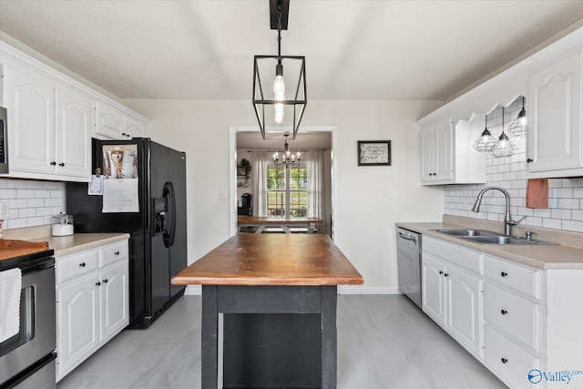 kitchen featuring white cabinets, stainless steel appliances, a sink, pendant lighting, and an inviting chandelier